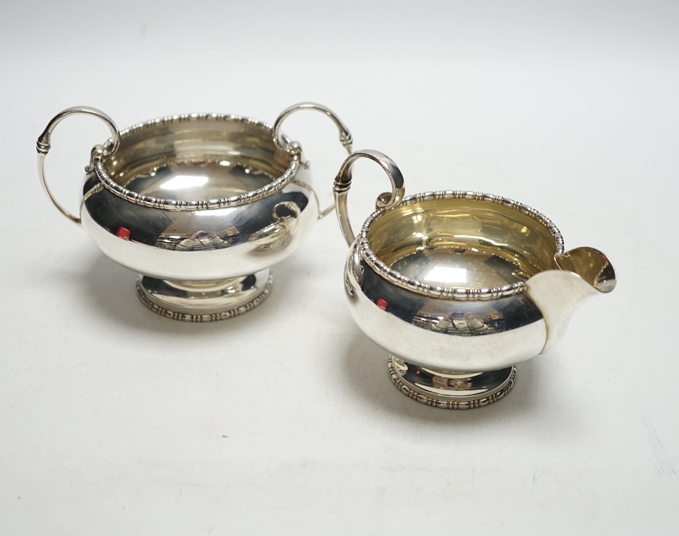 A George VI silver two handled sugar bowl and matching cream jug, Walker & Hall, Sheffield, 1950, 12.8oz.